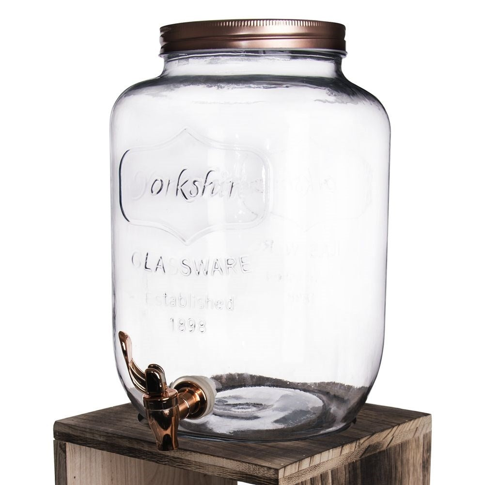 Un gran dispensador de vidrio con grifo y tapa de cobre.