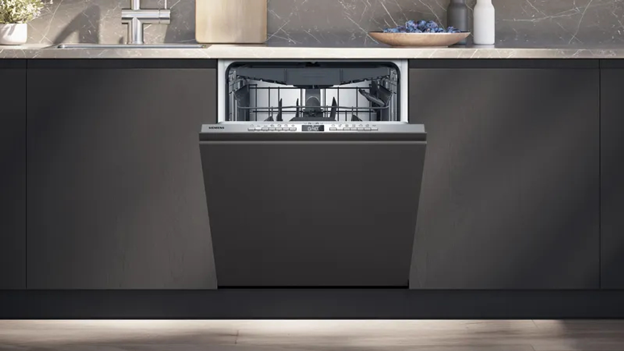 An open dishwasher with a silver front panel and control buttons.