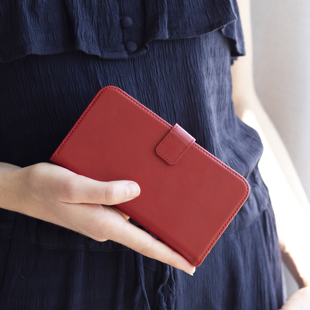 Una mano tiene una custodia rossa per telefono davanti a un vestito blu scuro.