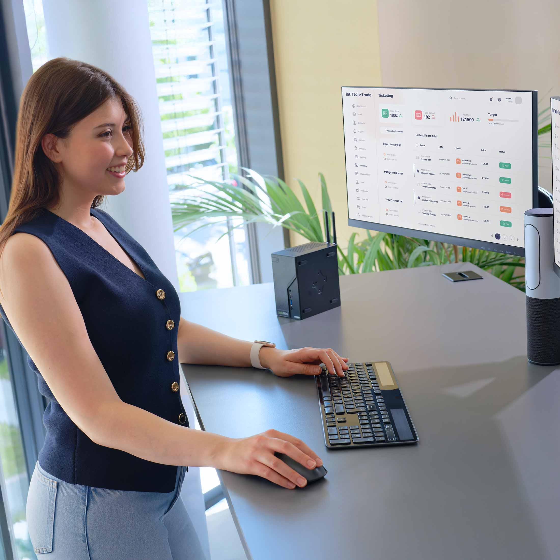 Eine Frau arbeitet an einem Schreibtisch mit zwei Monitoren und einer Tastatur.