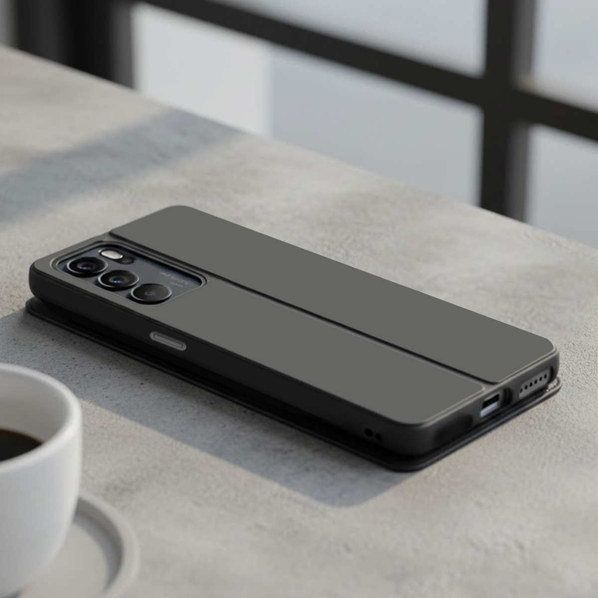 Una custodia scura per telefono su una superficie di cemento vicino a una tazza di caffè.