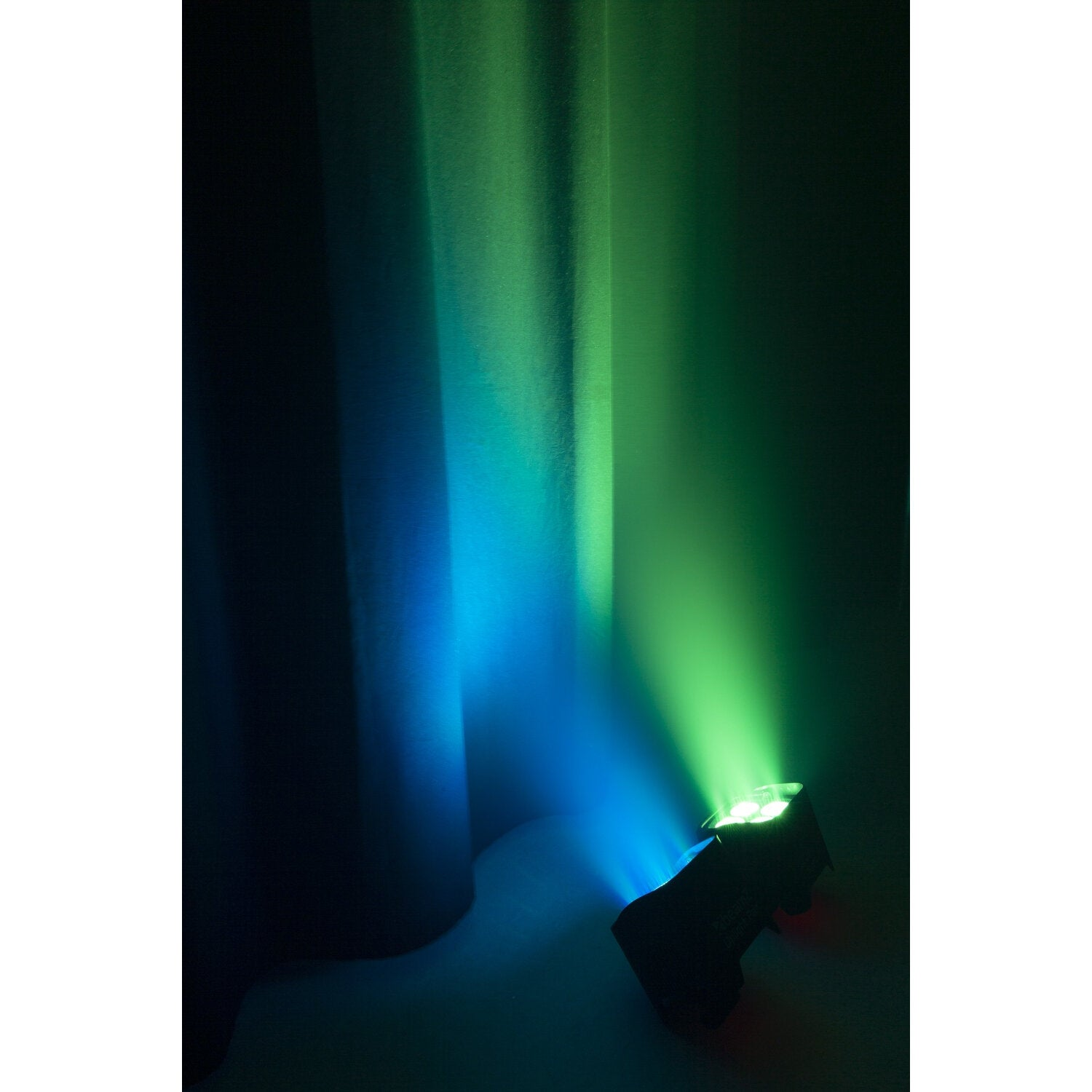 Un foco negro ilumina una pared con luz azul y verde.