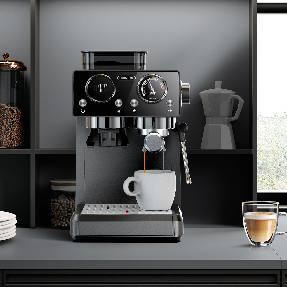 Una cafetera espresso prepara café en una taza blanca. Cerca hay un vaso de latte.