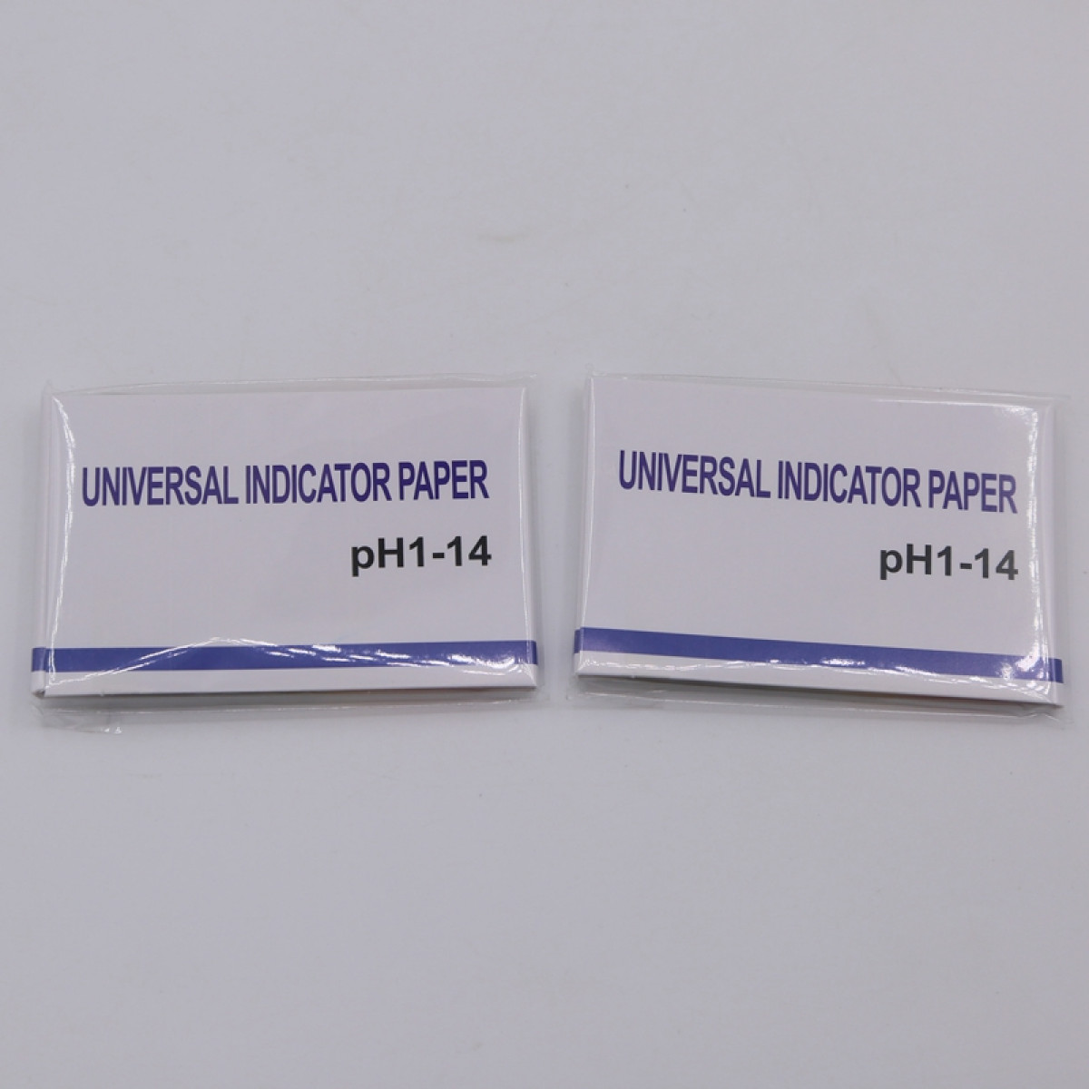 Dwa opakowania papieru uniwersalnego wskaźnikowego pH 1-14 na białym tle.