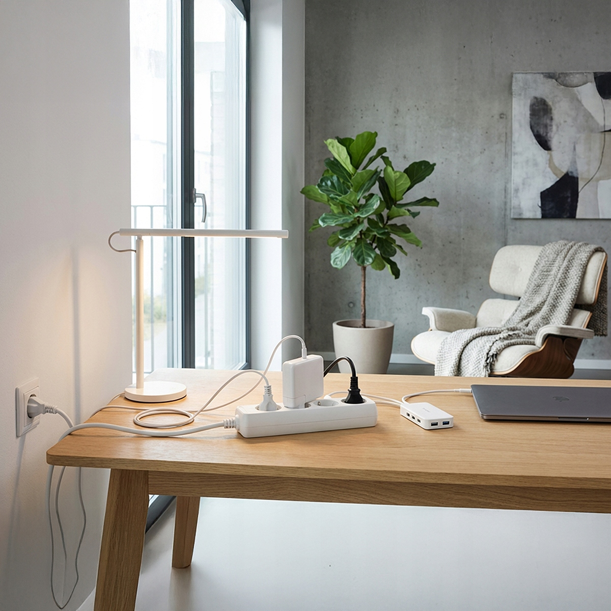 Biurko z lampą, listwą zasilającą, laptopem i krzesłem.