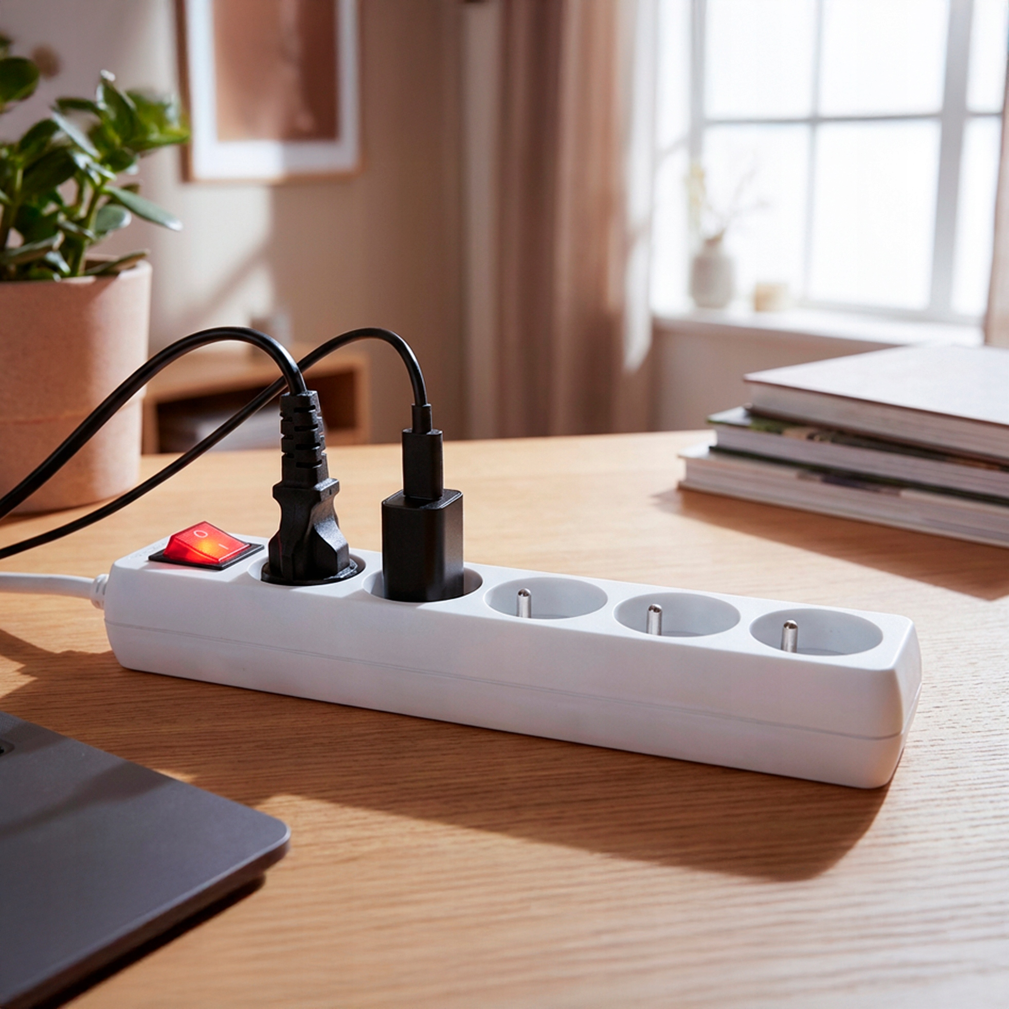 Biała listwa zasilająca z czerwonym przełącznikiem, podłączone wtyczki.