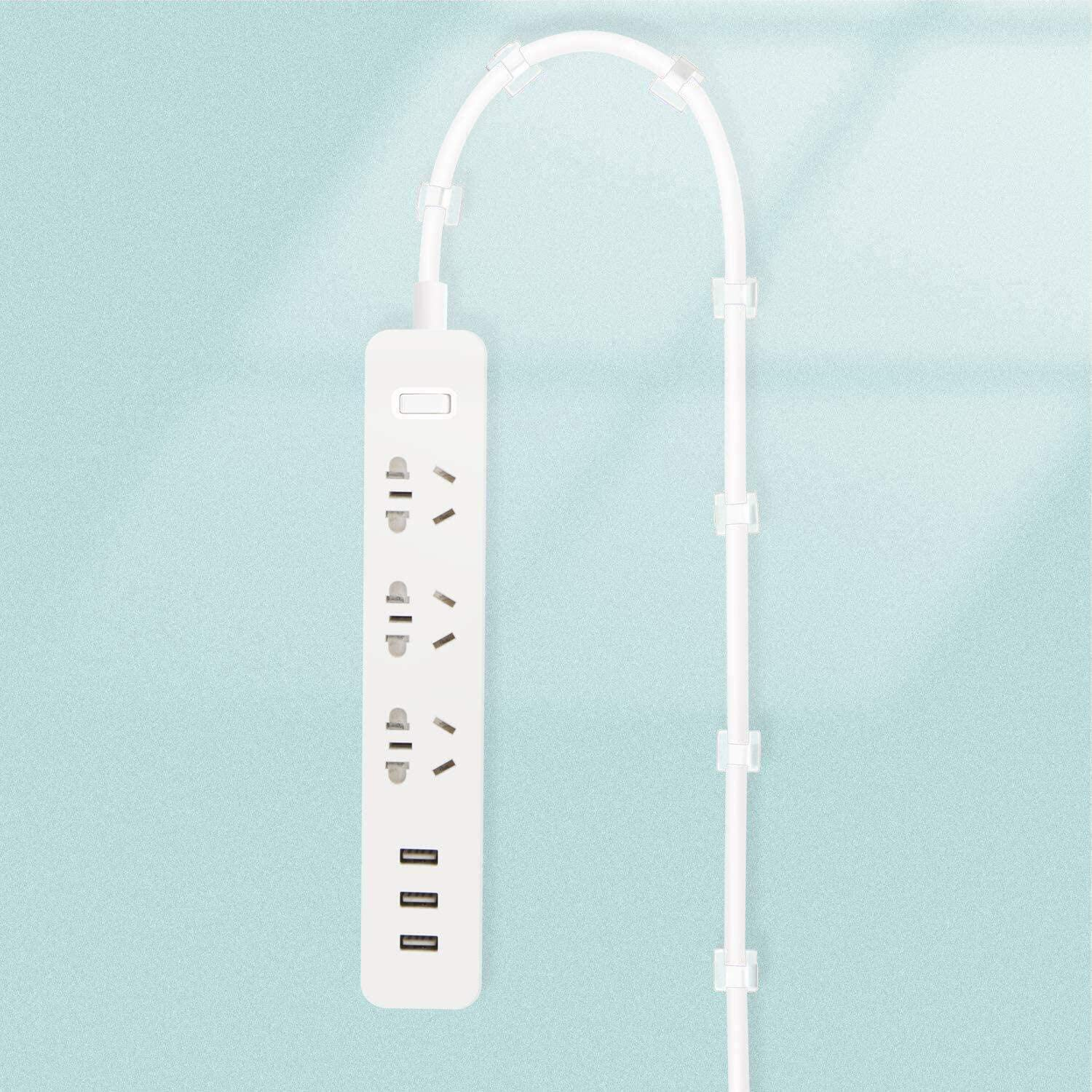 Biała listwa zasilająca z wieloma gniazdami i portami USB, przymocowana do turkusowej ściany za pomocą klipsów.