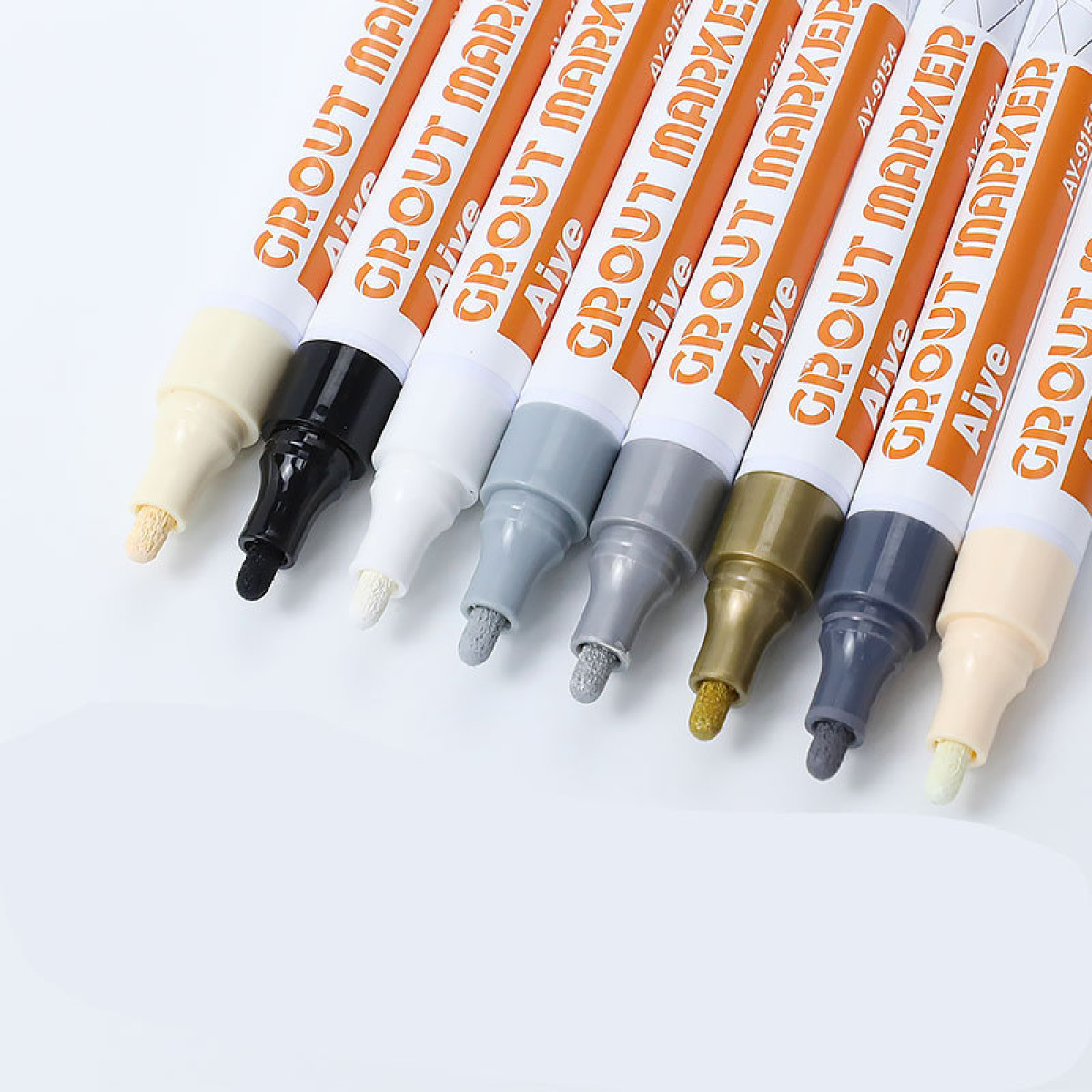 Kilka markerów do fug w różnych kolorach leży na białej powierzchni.