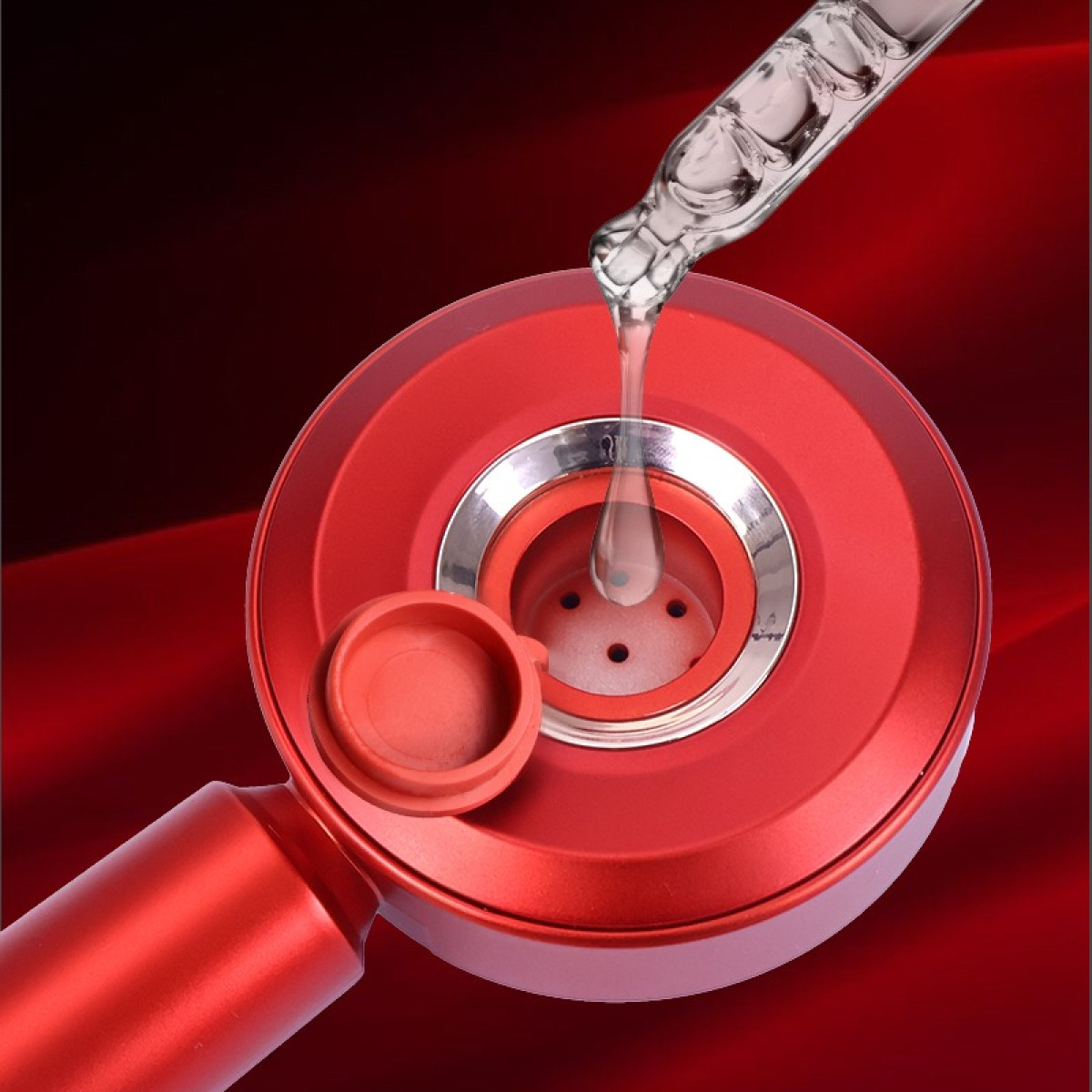 Kroplomierz dozuje płyn do czerwonej głowicy prysznicowej ze srebrnymi akcentami.
