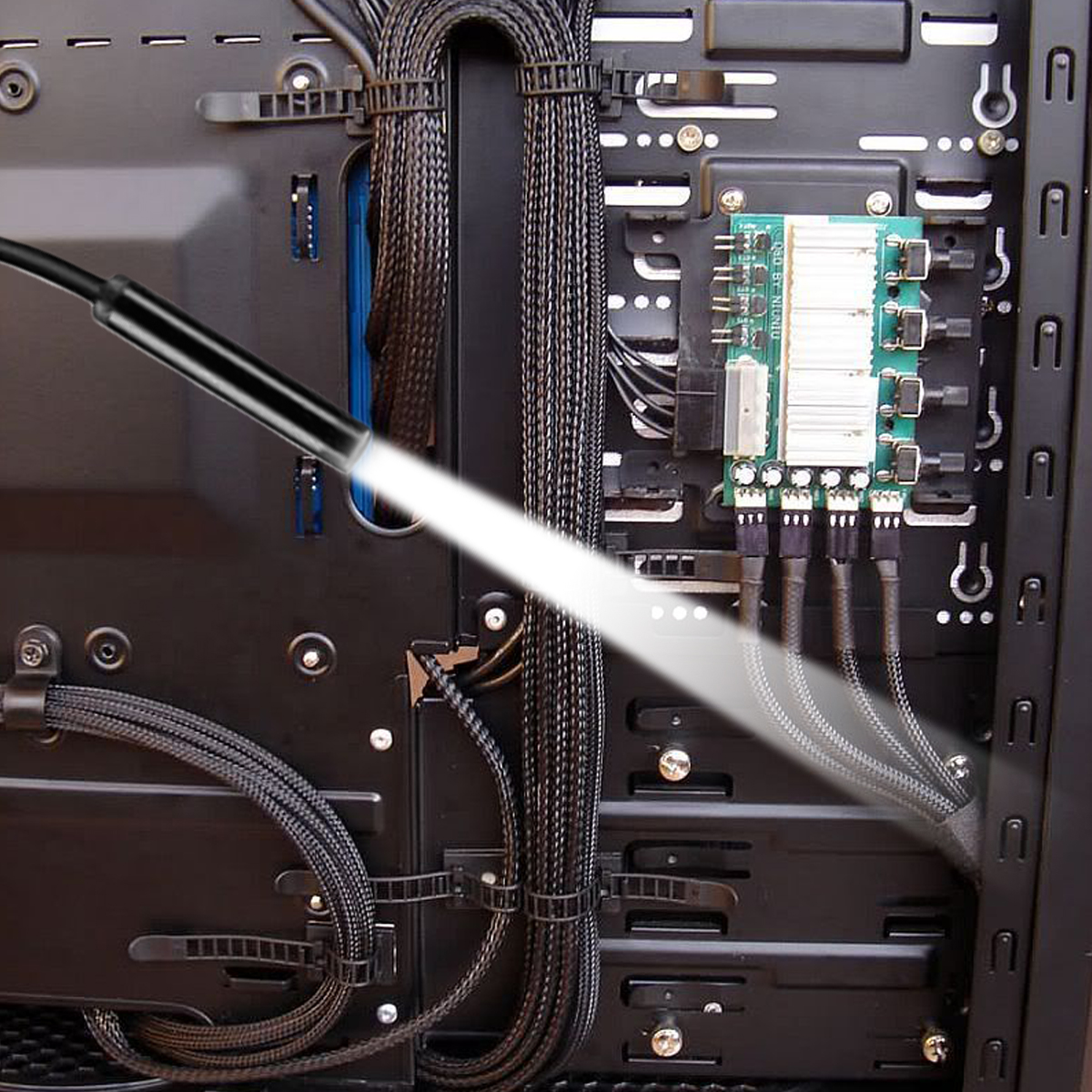 Endoskop świeci do otwartej obudowy komputera, oświetlając kable i płytkę drukowaną.