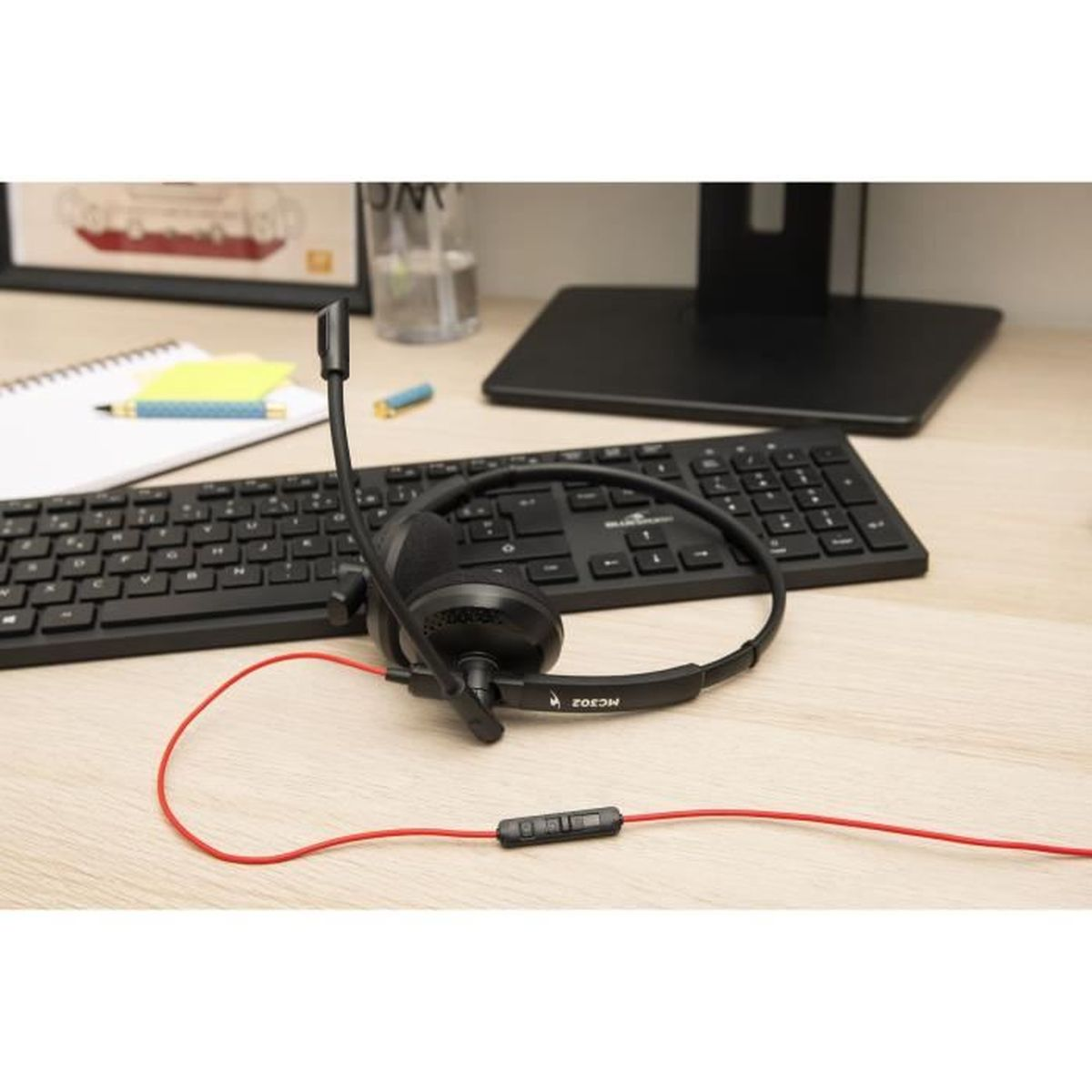 Ein schwarzes Headset mit rotem Kabel liegt vor einer Tastatur.