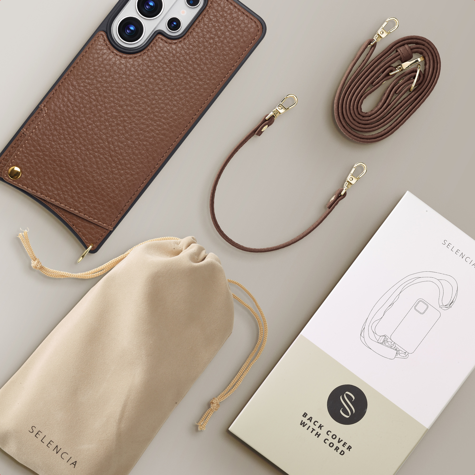 Bruine lederen telefoonhoes, koord, etui en doos op grijze achtergrond.