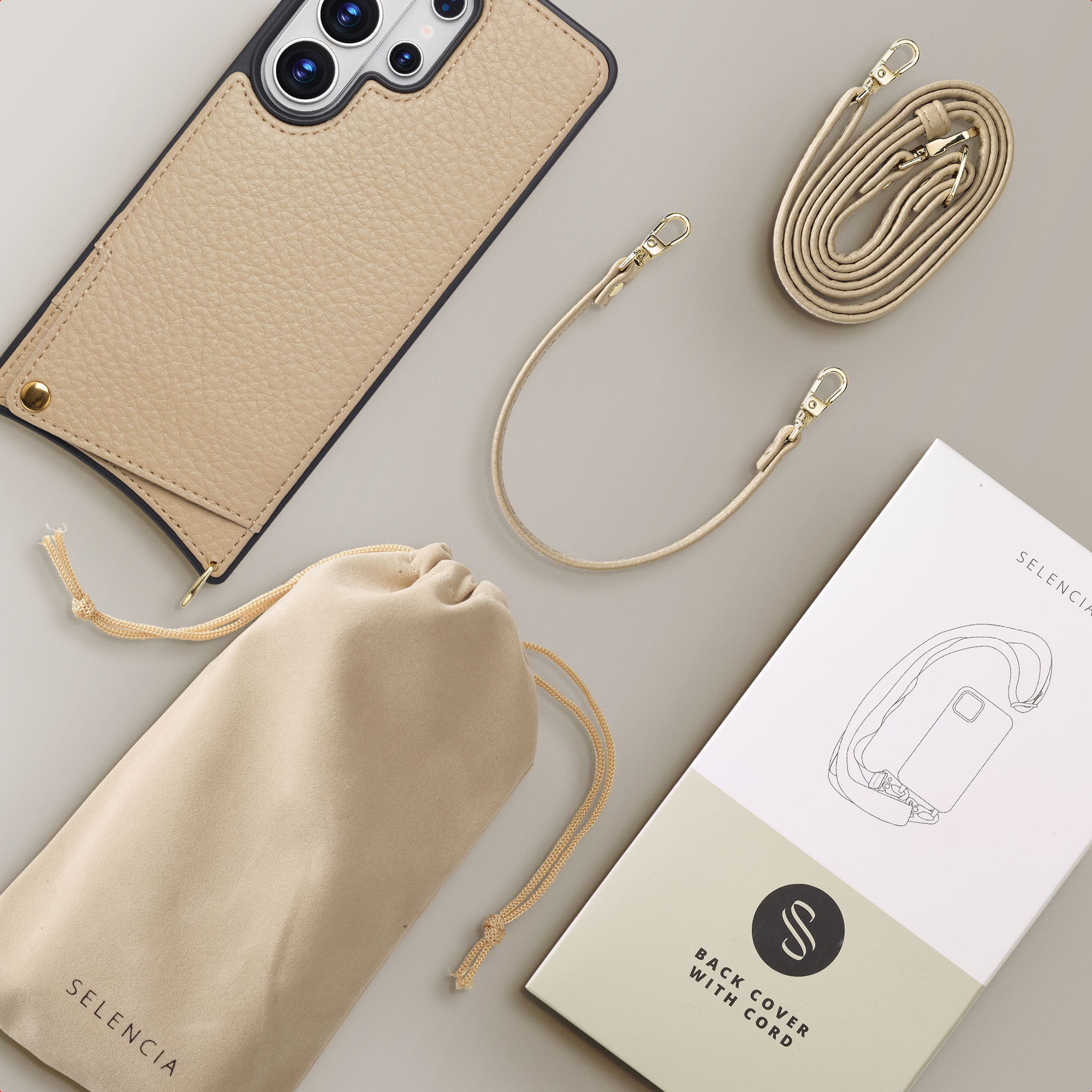 Een beige telefoonhoesje, koord, tasje en doos op een grijze ondergrond.
