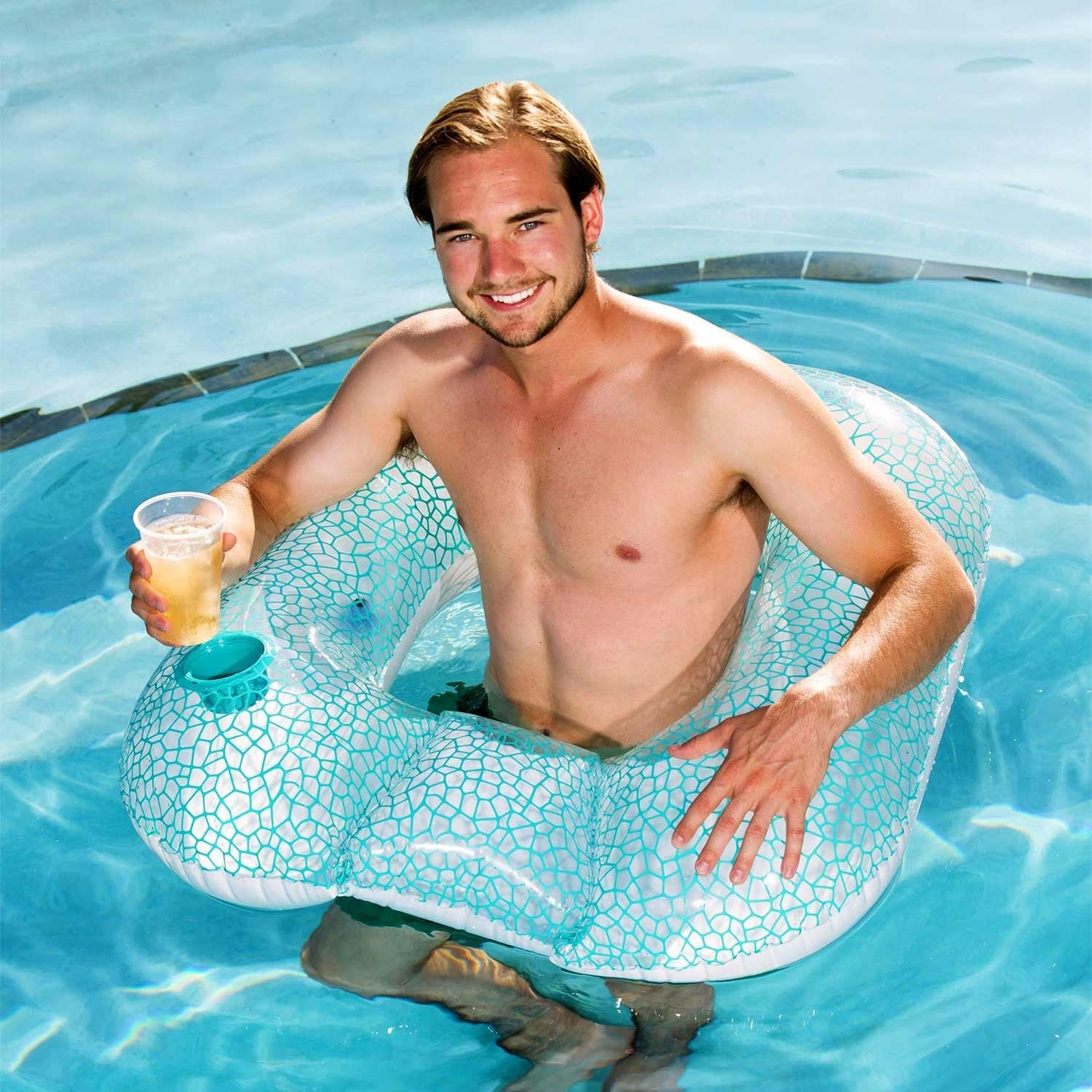 Un hombre en un flotador inflable con portavasos nada en la piscina.