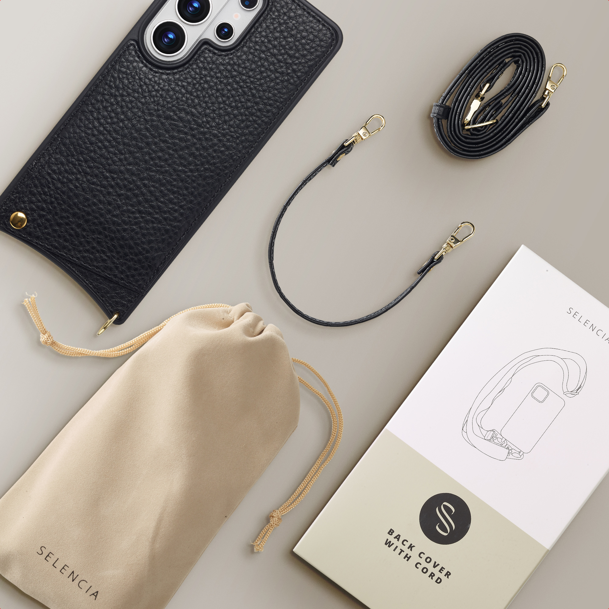Zwarte telefoonhoes met koord, etui en verpakking op grijze achtergrond.