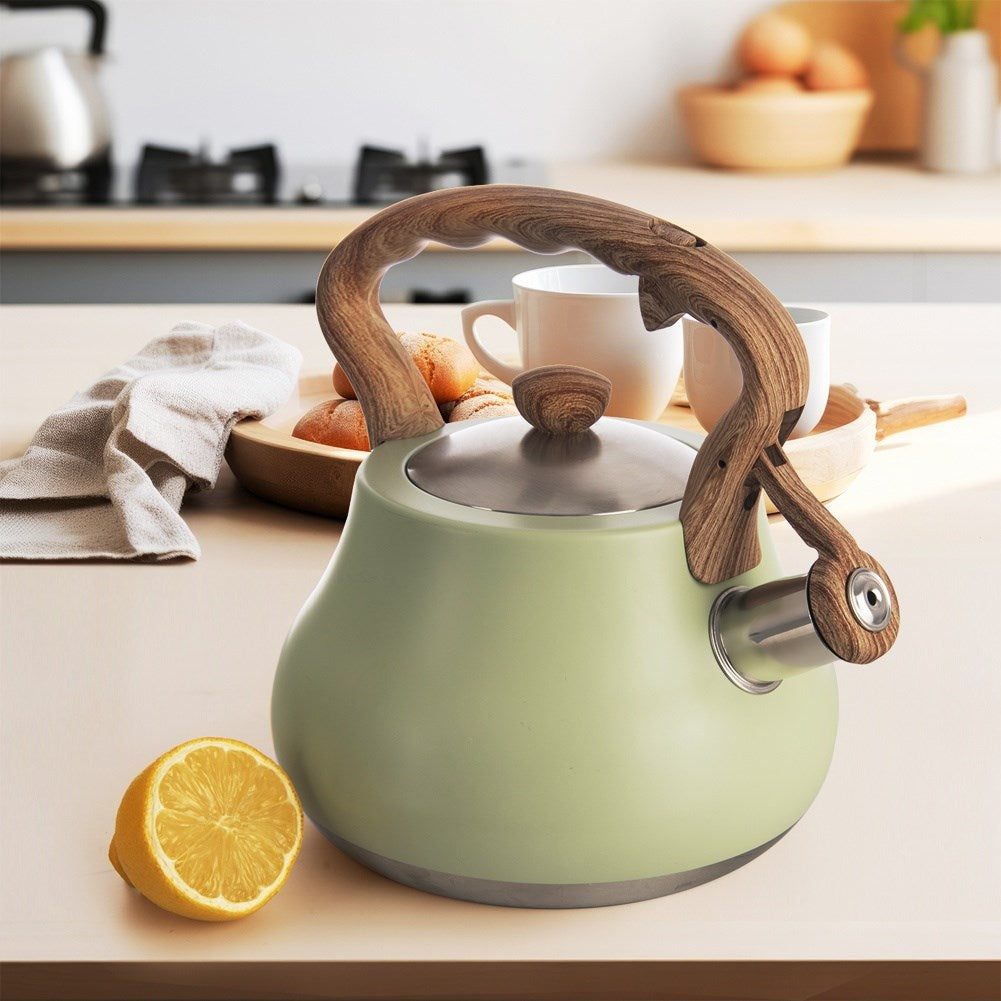Una tetera verde claro con mango de madera junto a un limón partido.