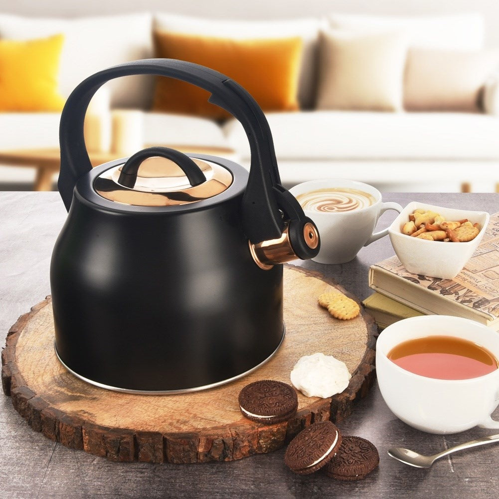 Tetera negra con detalles de cobre, galletas, café y té cerca.