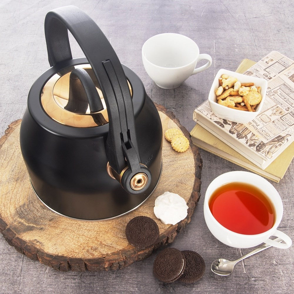 Tetera negra con detalles dorados, taza de té, galletas y libros sobre madera.