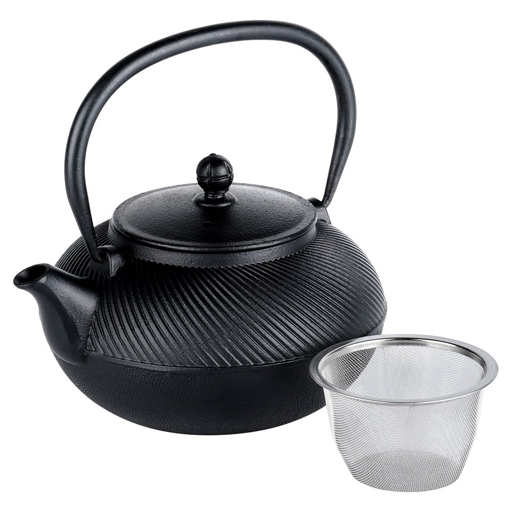 Tetera negra de hierro fundido con patrón acanalado y un colador de té al lado.