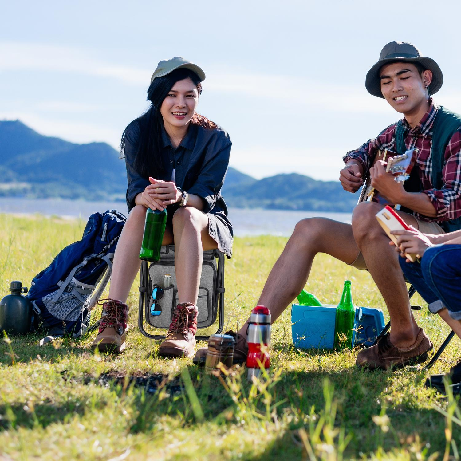 Dos amigos acampan junto a un lago, uno toca la guitarra, con montañas.