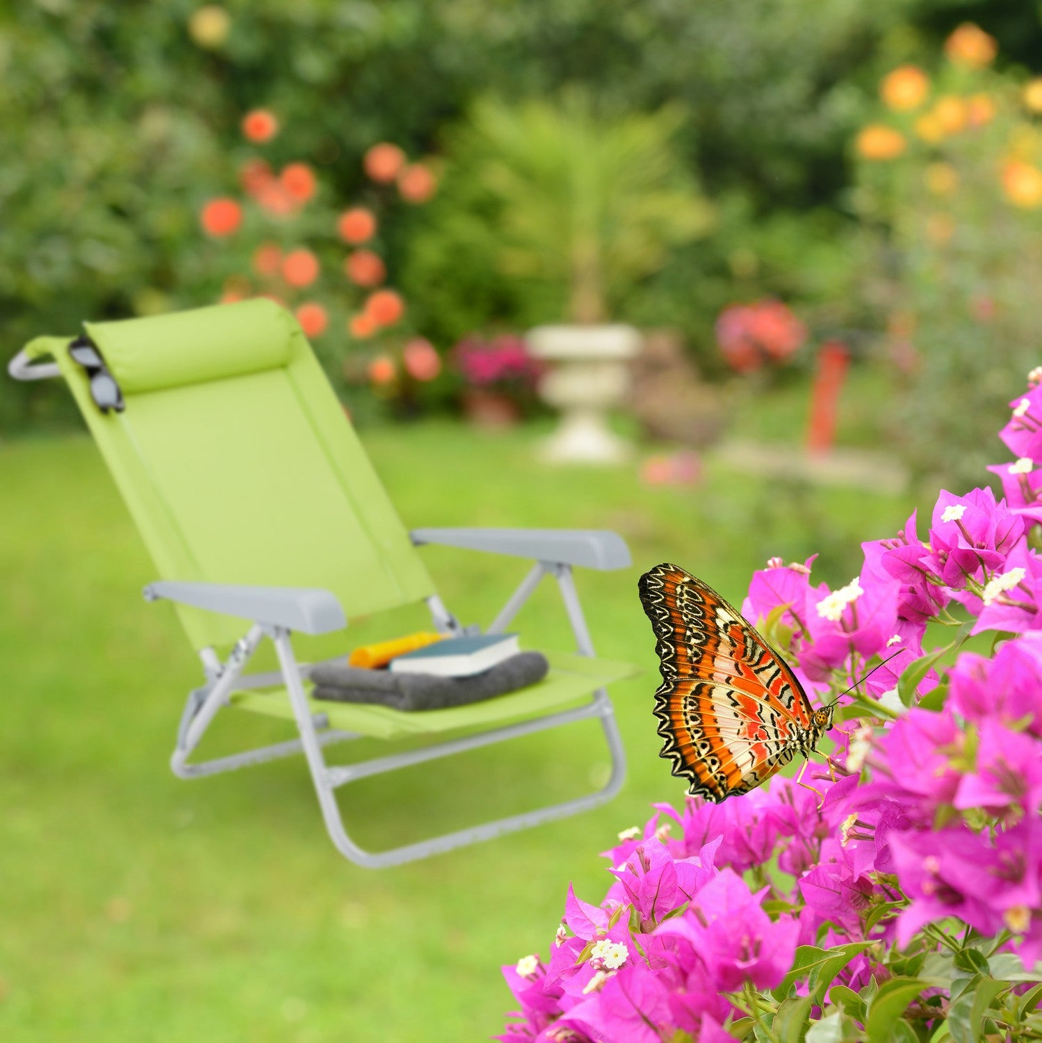 Una mariposa descansa sobre flores rosas junto a una tumbona verde en un jardín.