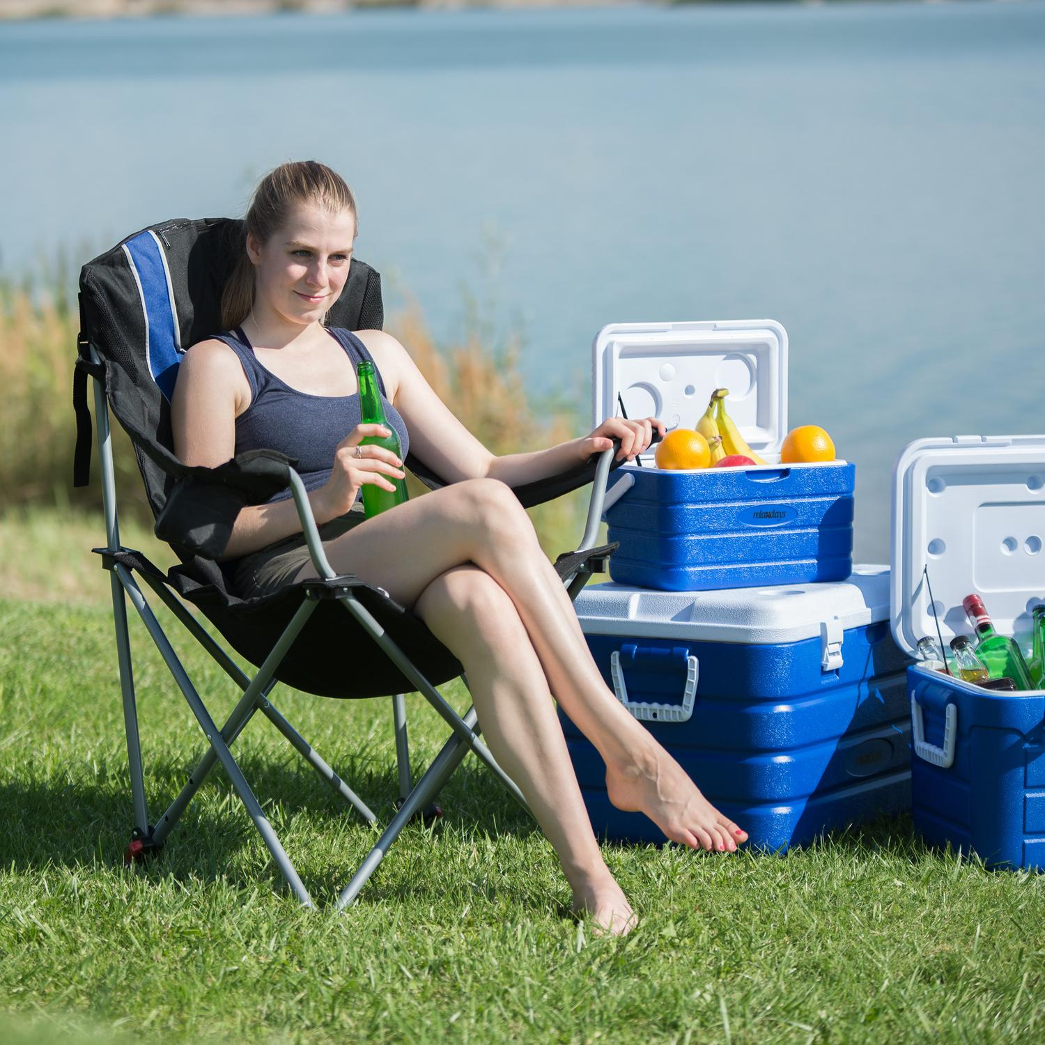 Una mujer sentada en una silla junto al lago bebiendo una botella.