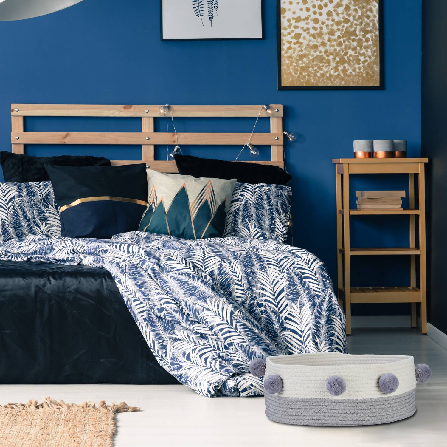 Un dormitorio azul con cama de madera, cojines estampados y una cesta de almacenaje.
