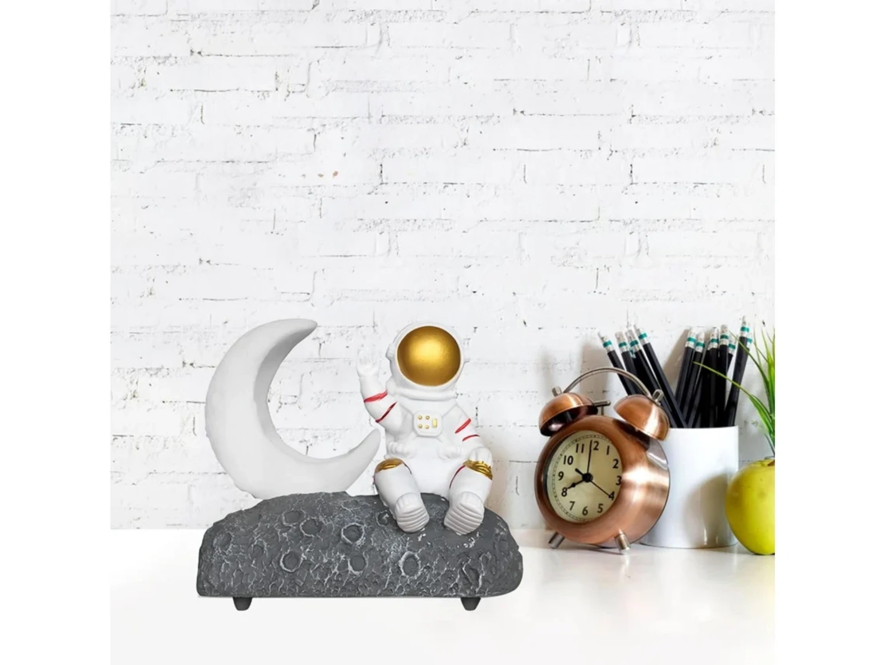 Ein Astronaut sitzt auf dem Mond neben einer Mondsichel, Uhr und Stiften.