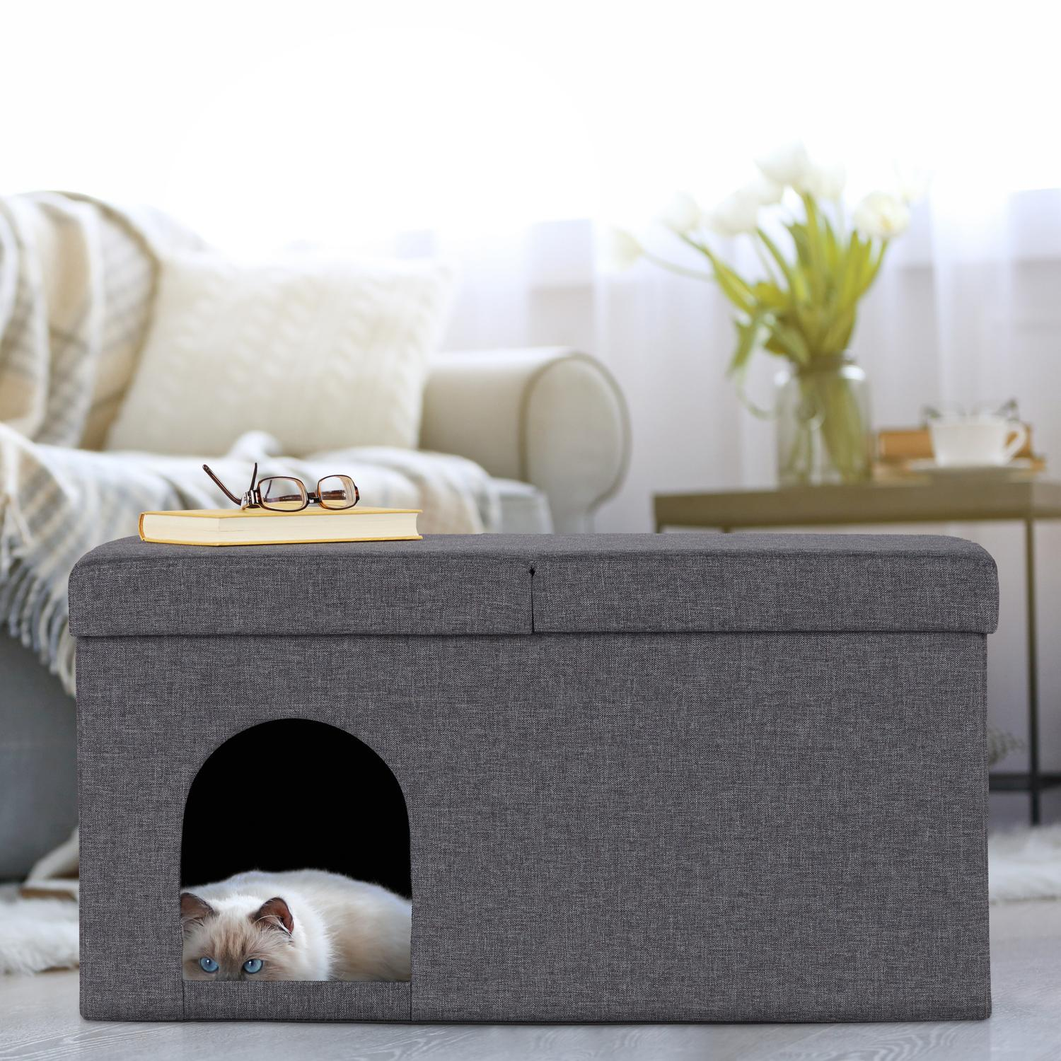 Casa de gato gris con abertura redonda, que alberga un gato de ojos azules.