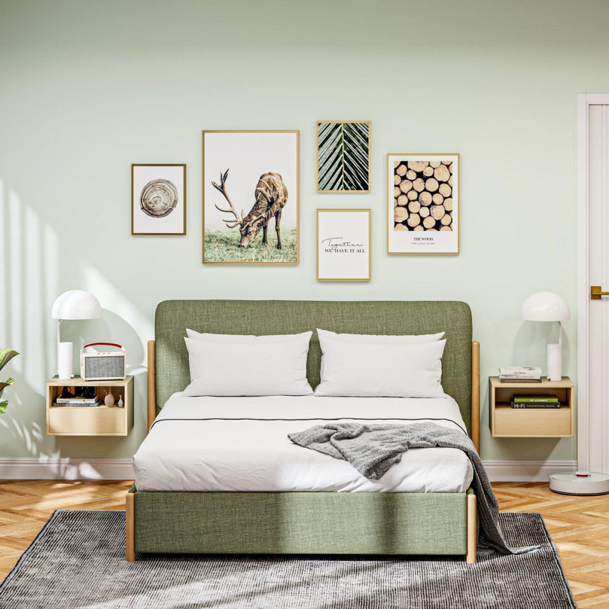 Ein grünes Bett mit weißen Kissen und einer Decke steht in einem Raum mit Kunst an der Wand.