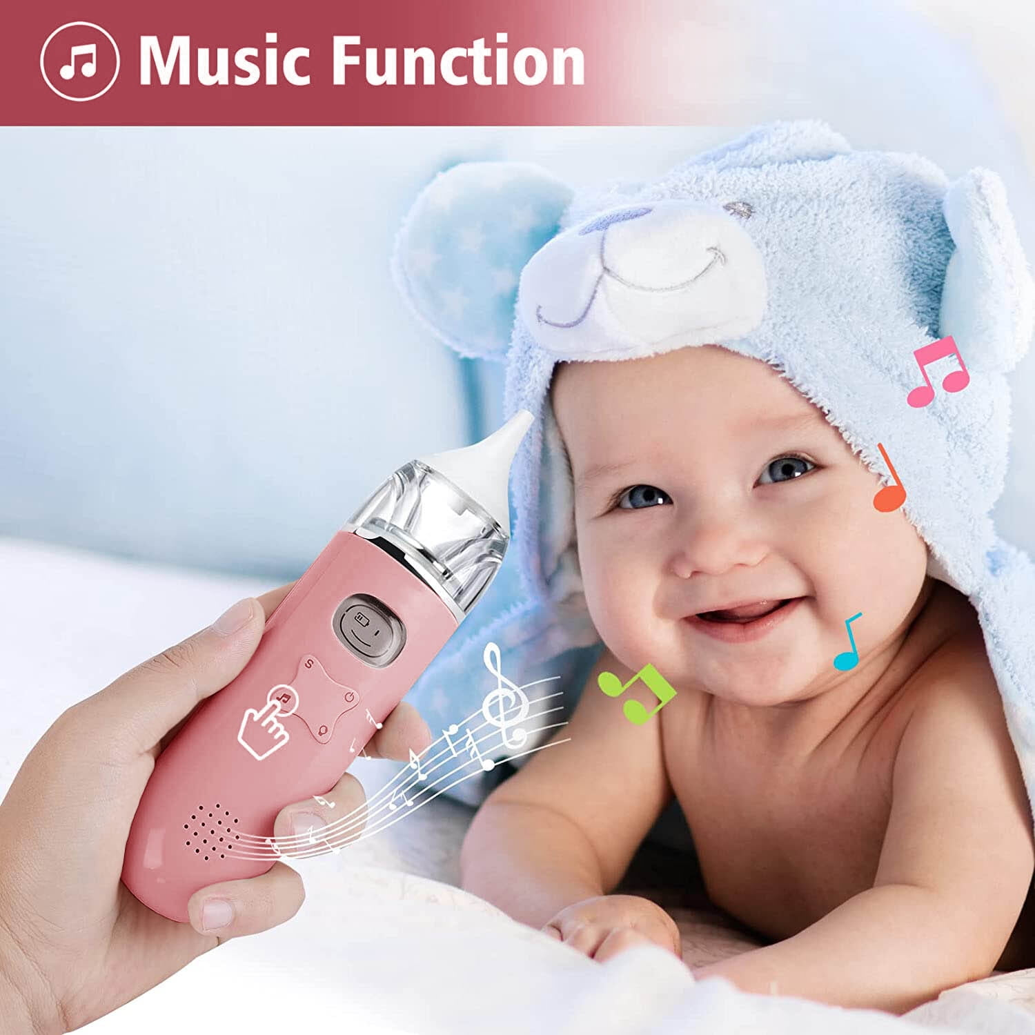 Ein Baby mit Bärenmütze lächelt, während eine Hand ein rosa Nasensauger hält.