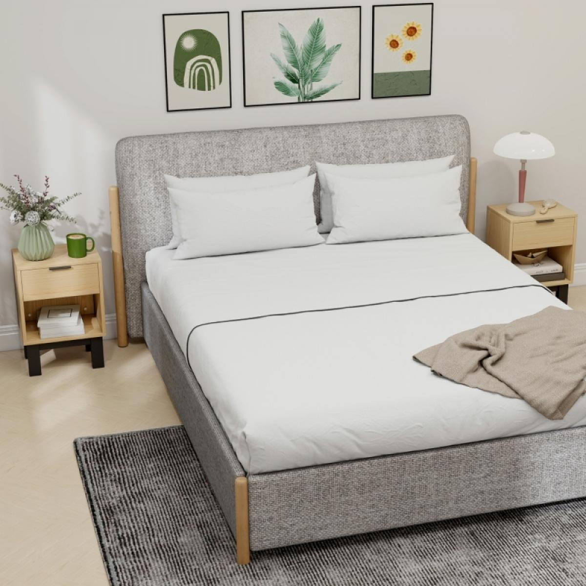Ein modernes Schlafzimmer mit einem grauen Stoffbett, weißen Kissen, Nachttischen und Kunst an der Wand.