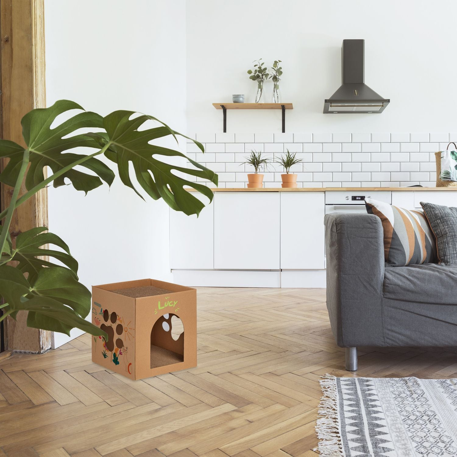Una casa para gatos de cartón con patrones coloridos se asienta en un suelo de madera.