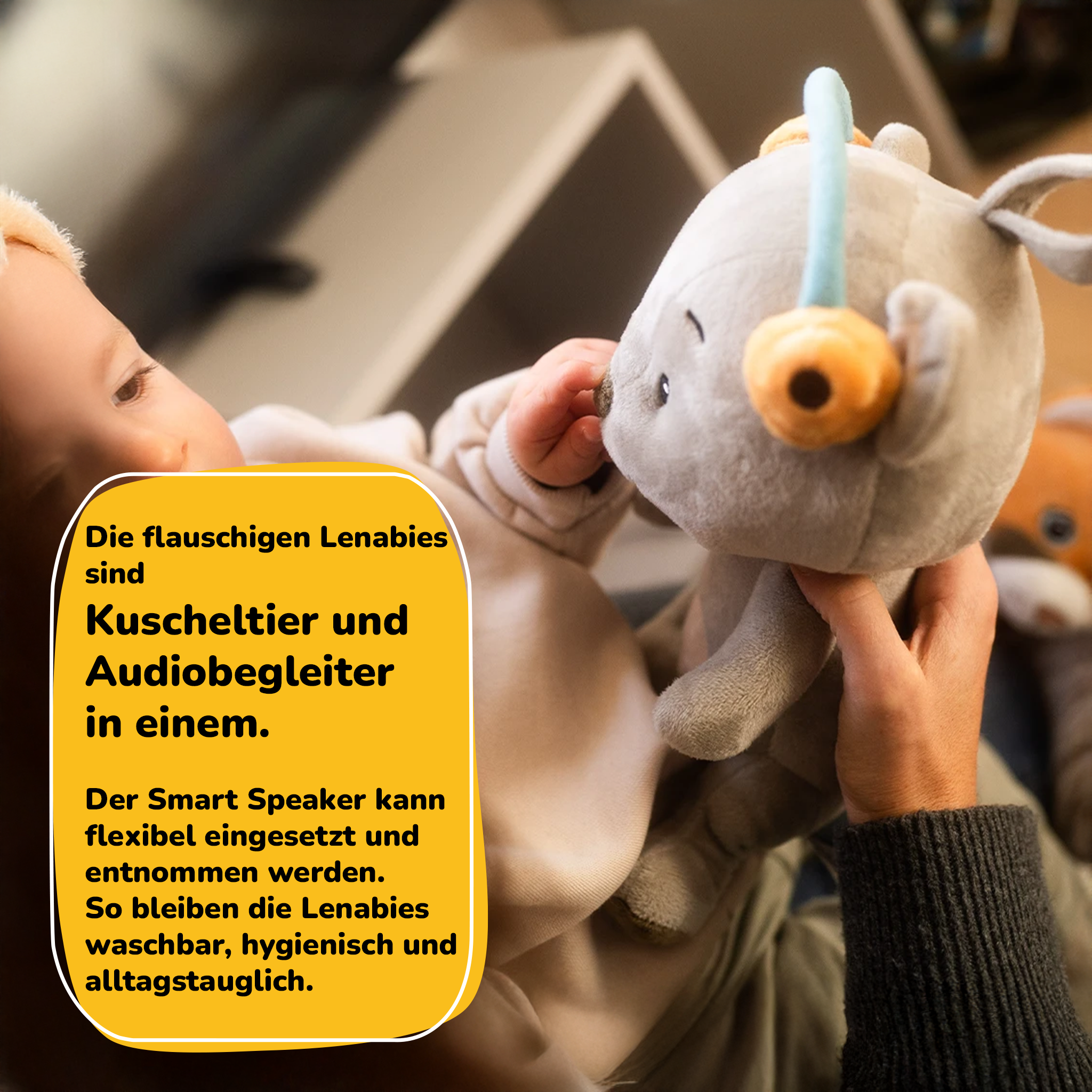 Ein Baby hält ein graues Plüschtier mit Kopfhörern. Ein gelber Kasten erklärt.