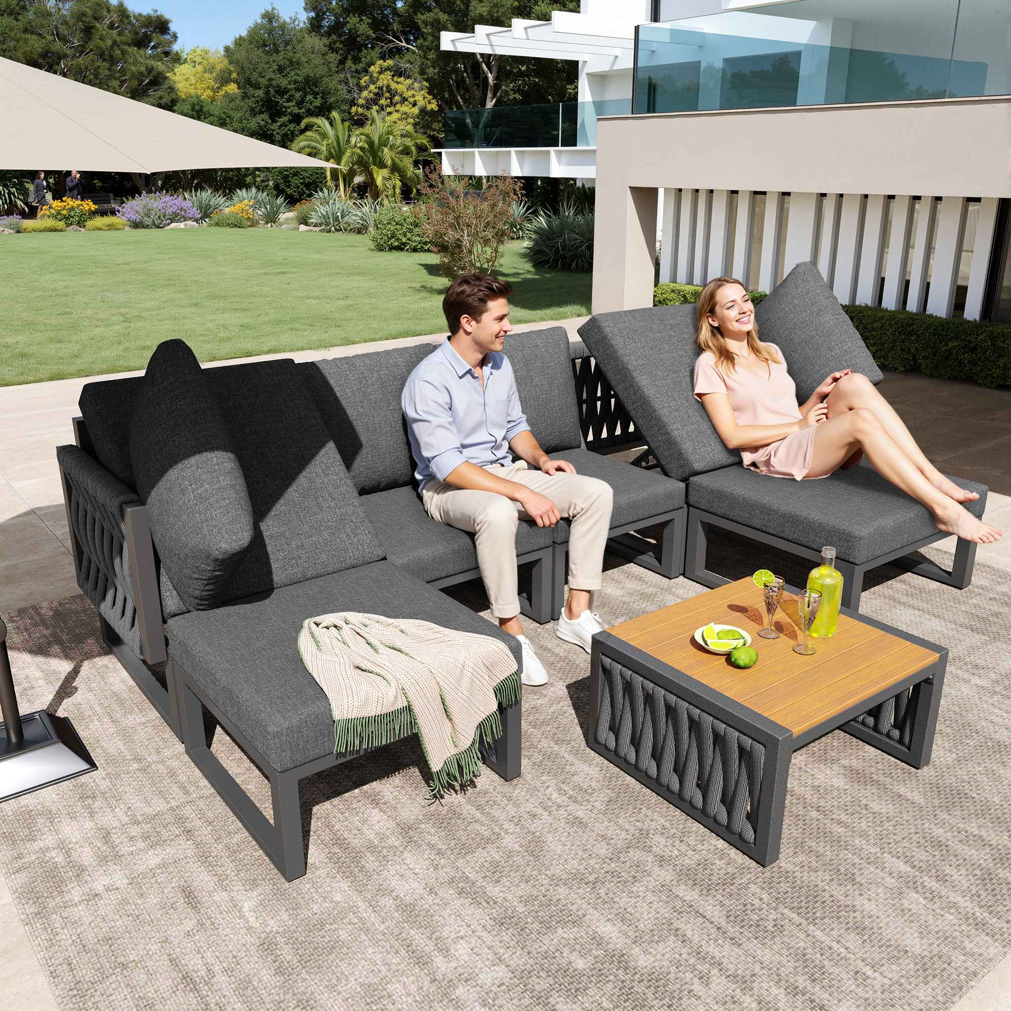 Ein Mann und eine Frau entspannen sich auf einem grauen Lounge-Set im Garten.