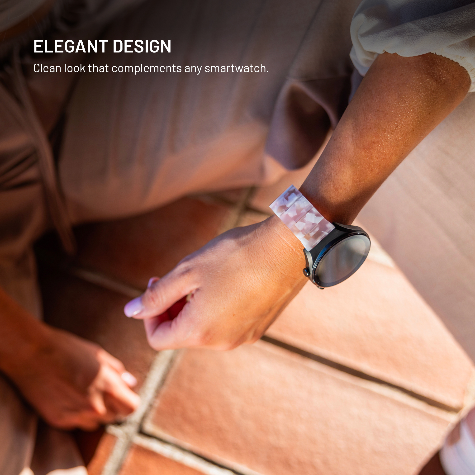 Nahaufnahme eines Arms mit einer Smartwatch mit einem marmorierten Armband auf einem Terrazzoboden.