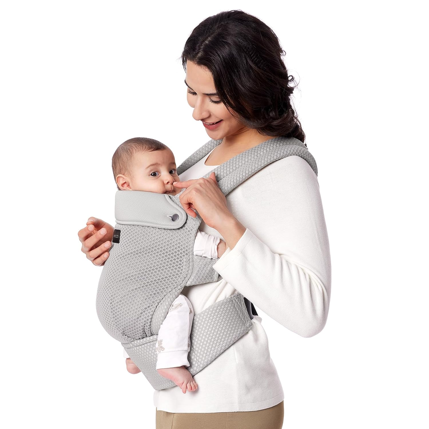 Una donna porta un bambino in un marsupio grigio su sfondo bianco.
