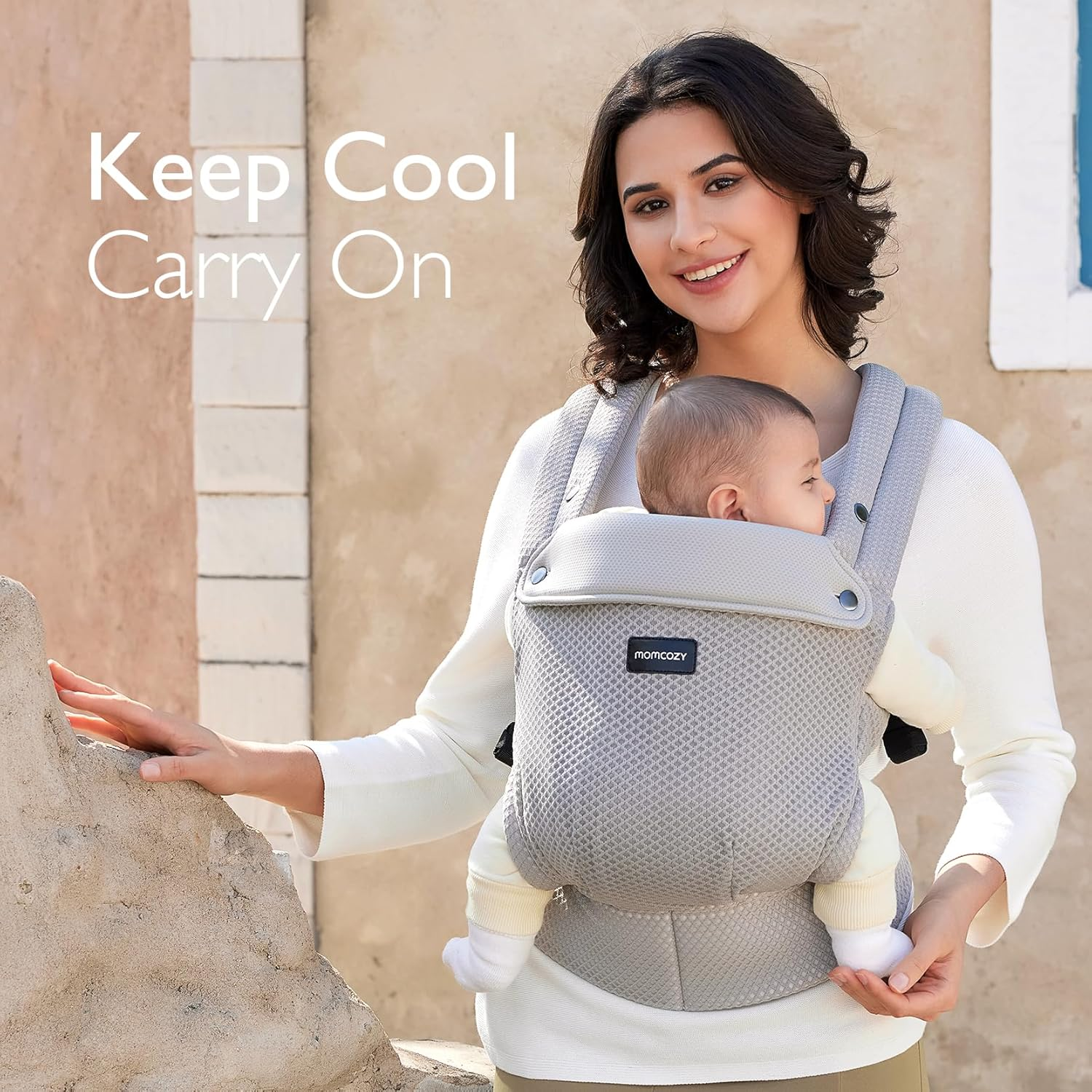 Una donna porta un bambino in un marsupio grigio. All'aperto, soleggiato.