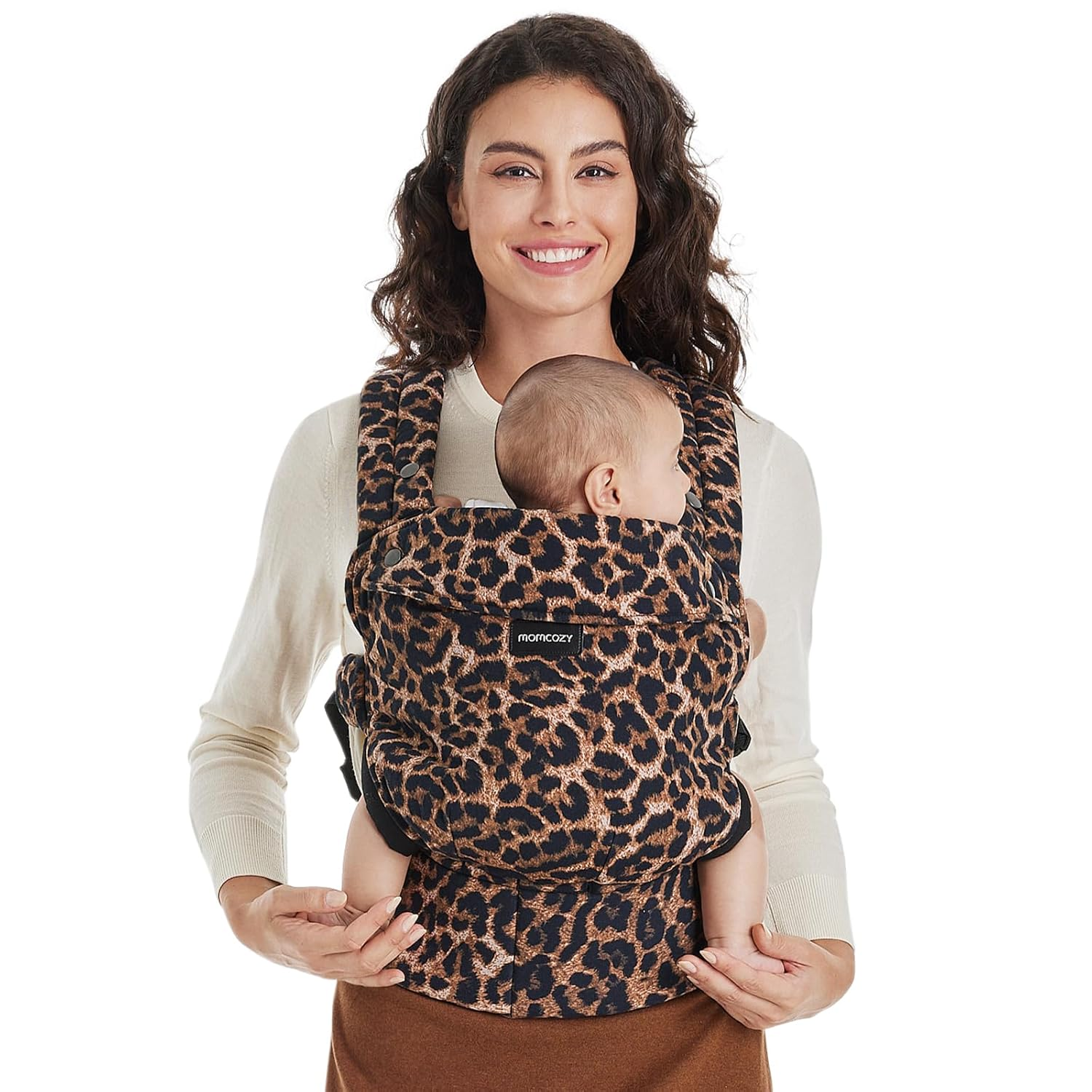 Donna sorridente con neonato in marsupio leopardato. Sfondo bianco.