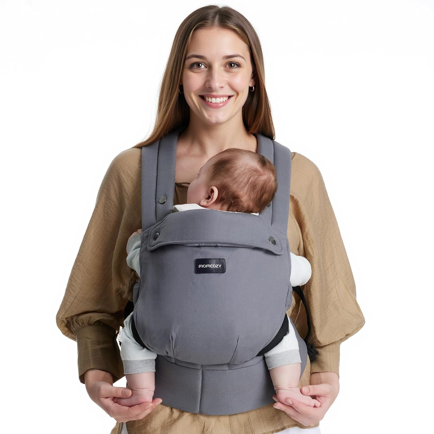 Una donna sorride mentre porta un bambino in un marsupio grigio.