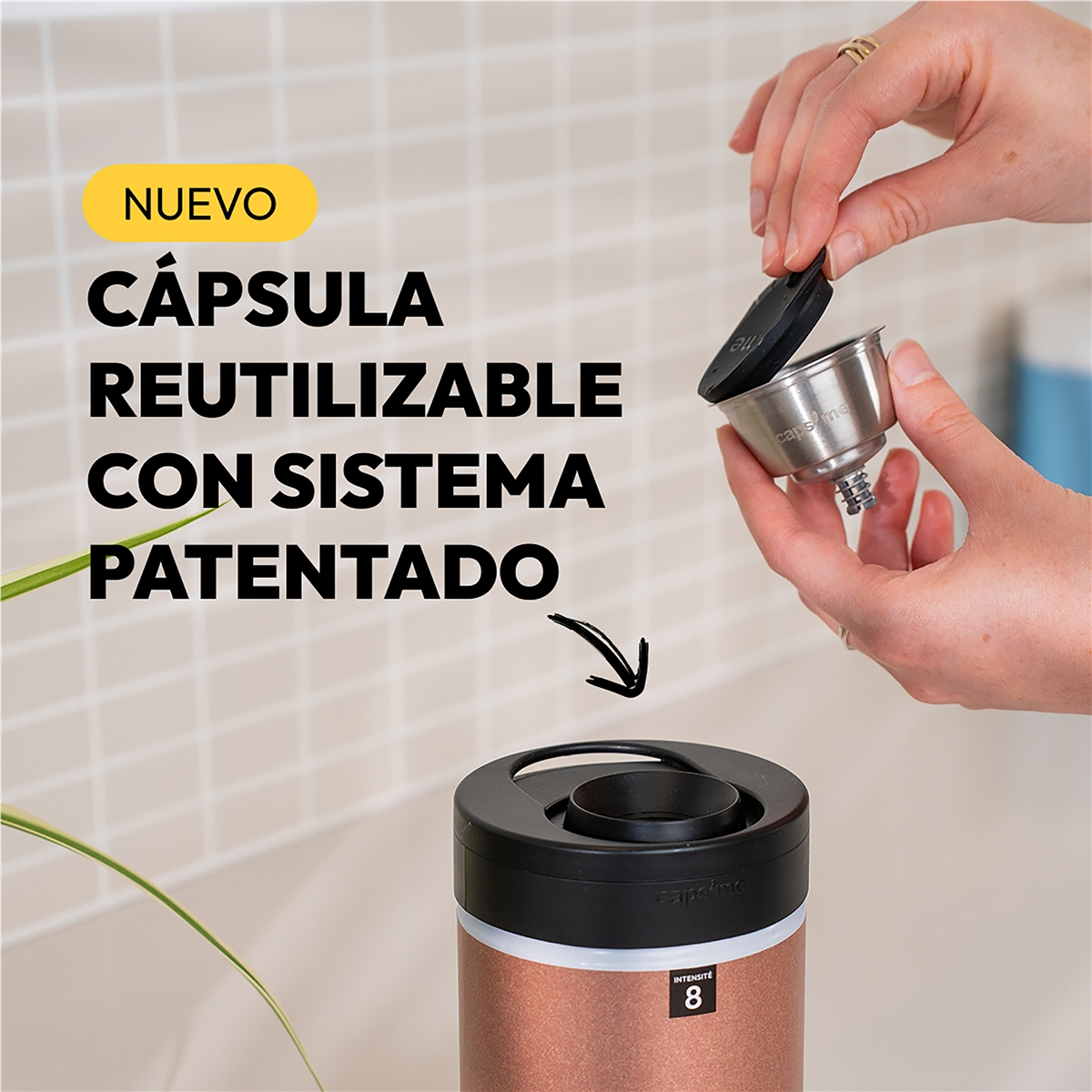 Manos sujetan una cápsula de café metálica reutilizable sobre una cafetera color oro rosa.