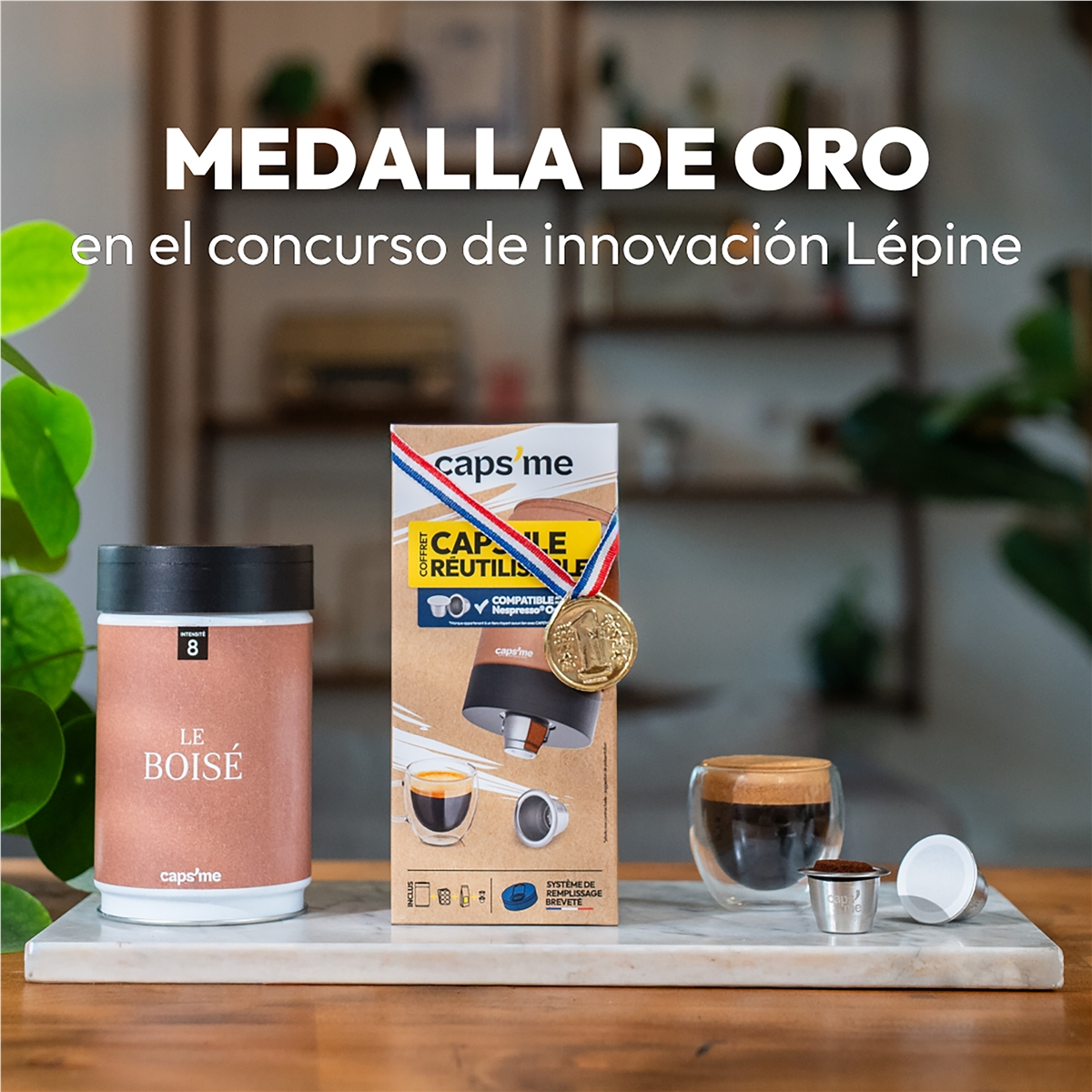 Un vaso de café, cápsulas de café y un recipiente sobre mármol. Medalla de oro.