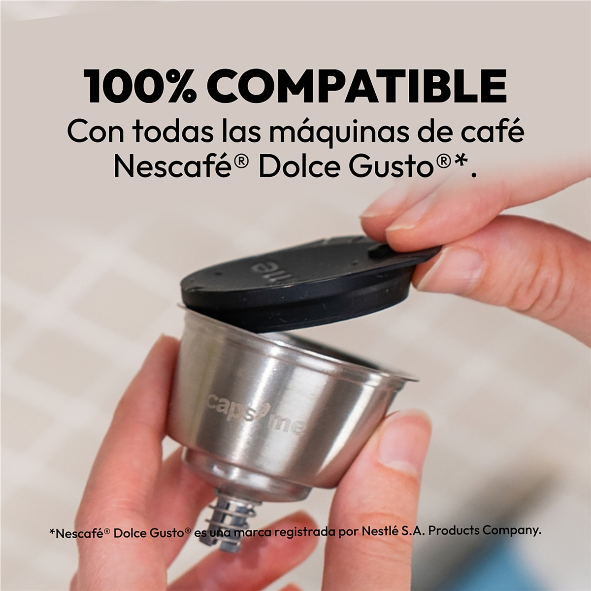 Una mano sostiene una cápsula de café metálica reutilizable.
