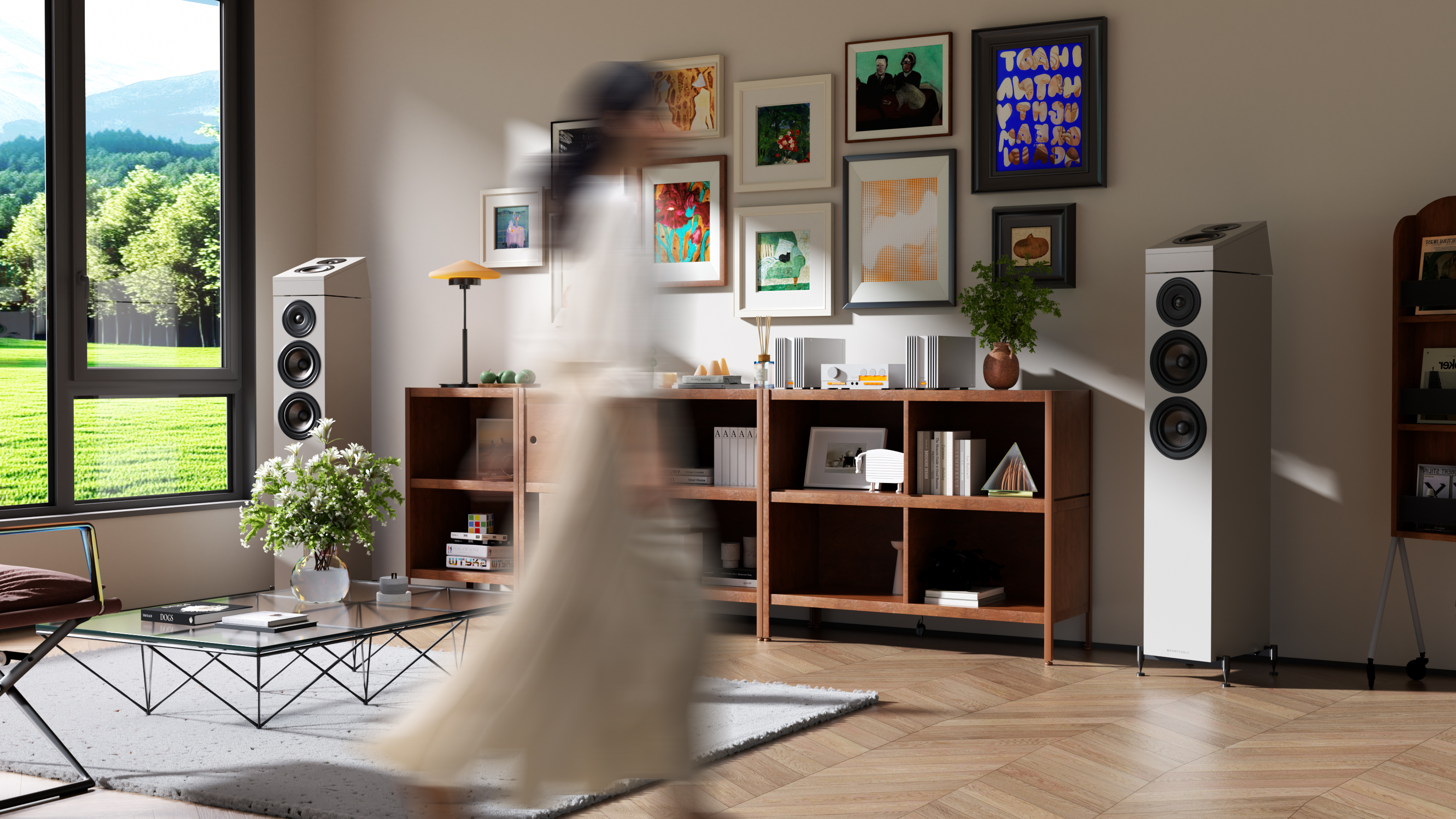Een lichte woonkamer met twee witte luidsprekers, boekenplanken en kunst aan de muur.