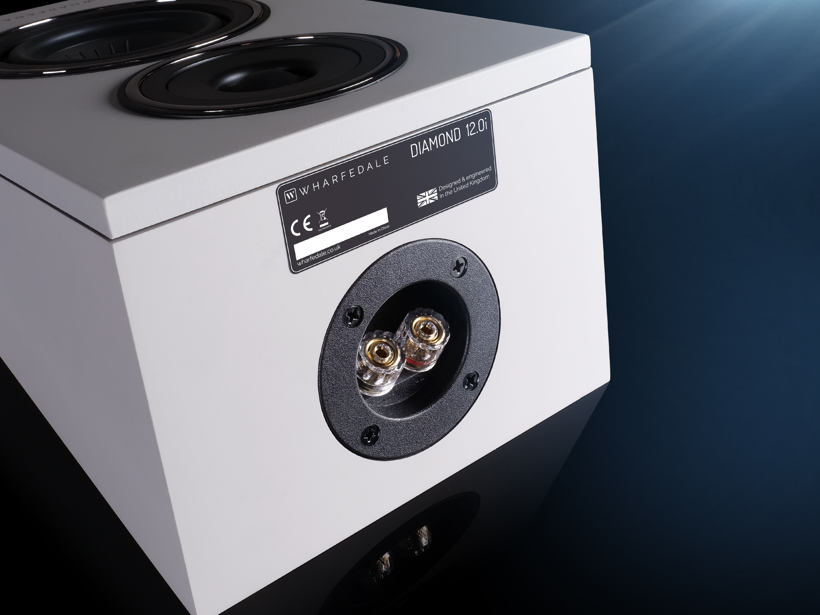 Rear of a white speaker with two terminals and a label.