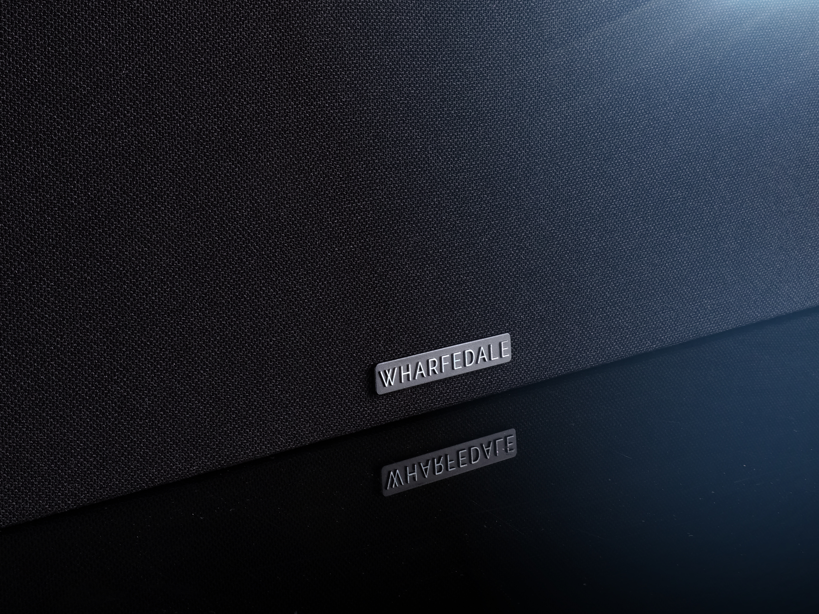 Close-up van een zwarte luidspreker met zilveren WHARFEDALE logo.