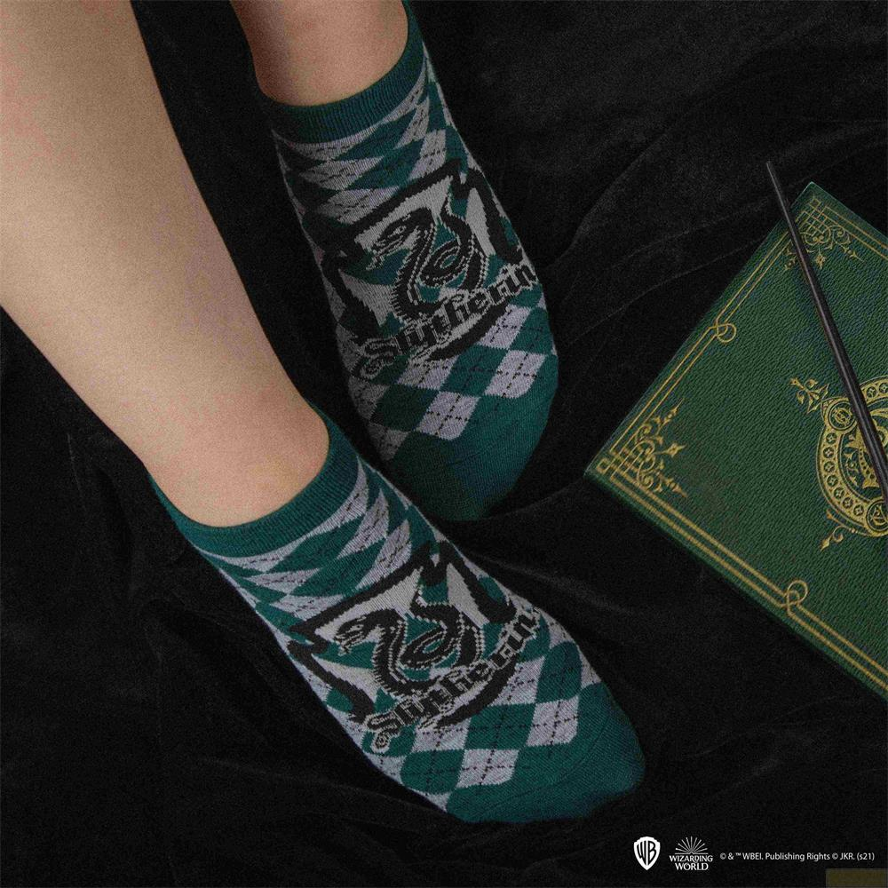 Grüne Socken mit Slytherin-Logo und Rautenmuster auf schwarzem Hintergrund.