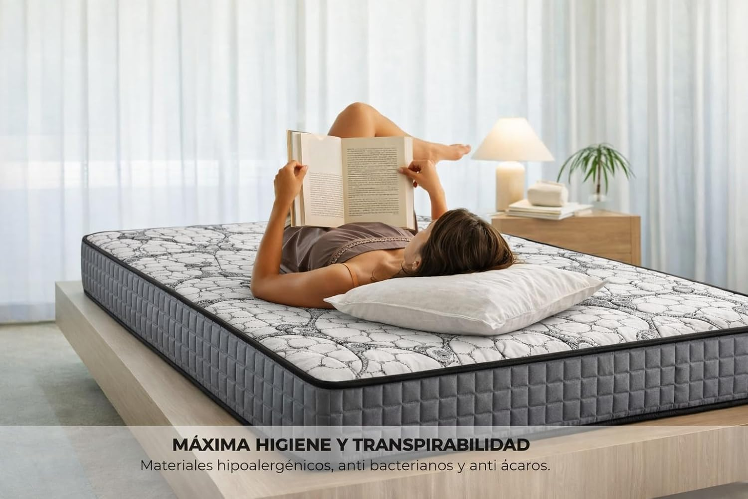 Una mujer yace en una cama leyendo un libro. La cama tiene una manta estampada.
