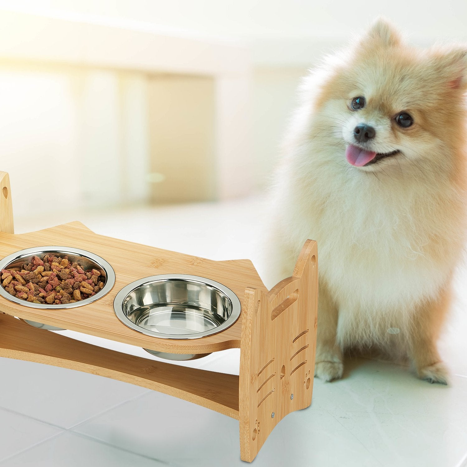 Un pequeño Pomerania se sienta junto a un comedero de madera con cuencos de comida y agua.