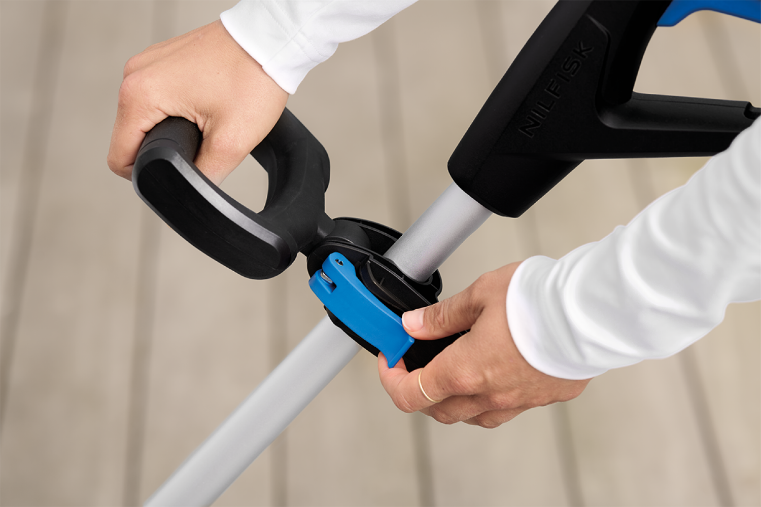 A hand in a white sleeve adjusts a blue lever on a NIlfisk device.
